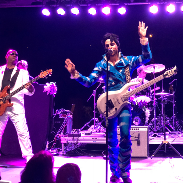 Marshall Charloff as Prince along with a bandmate on stage. Marshall's hands are raised as he sings.