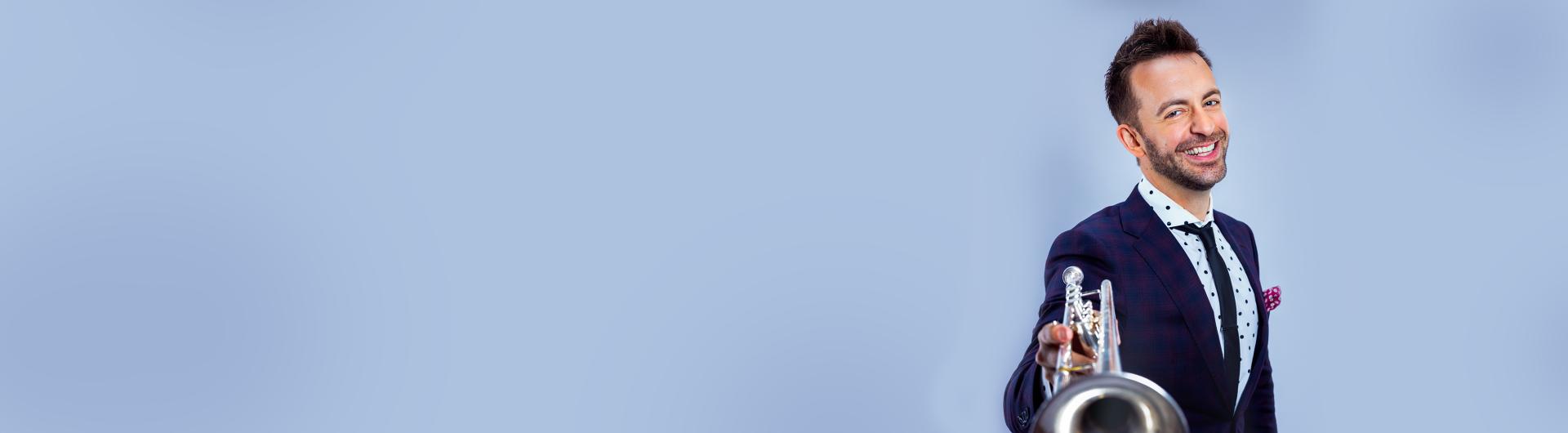 Benny smiling at the camera and holding out his silver trumpet.